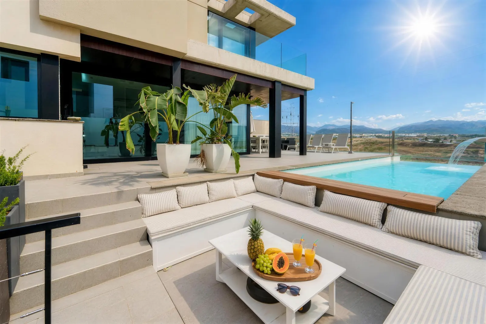 Lounge area by the pool with banana plants in planters and the house behind