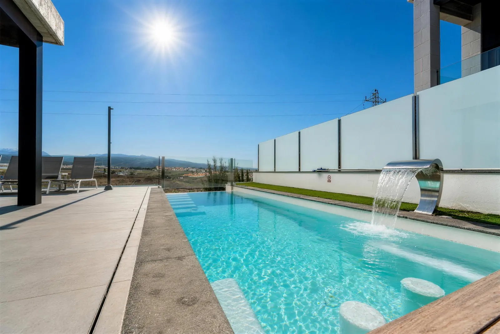 Private pool with steel waterfall and in-water seats, mountains in the distance