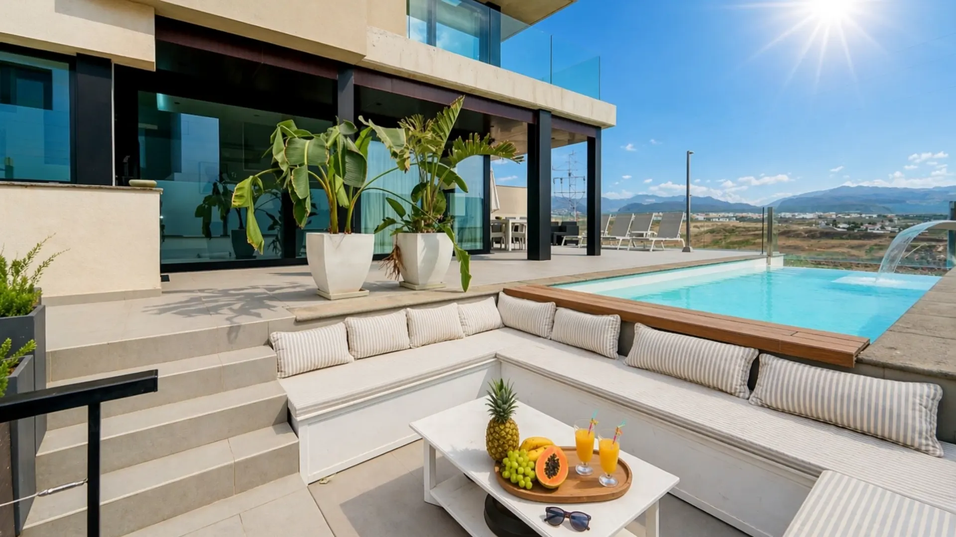 Lounge area by the pool with banana plants in planters and the house behind